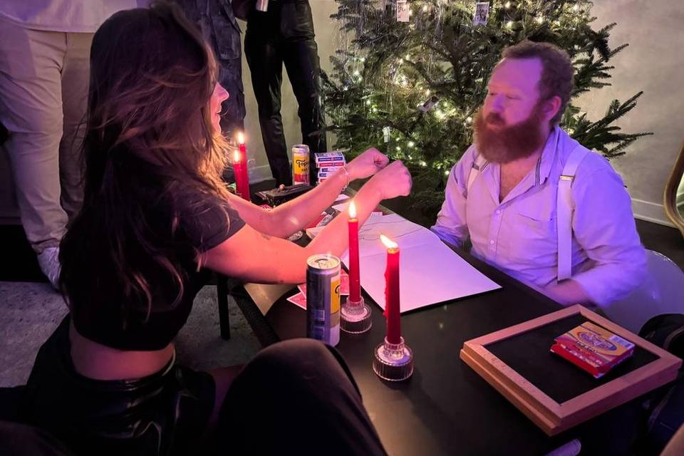 Timothy Starnes performing close-up magic with a guest at a candlelit table